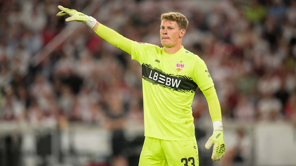 Alexander Nübel zeigt im Trikot des VfB Stuttgarts nach links.