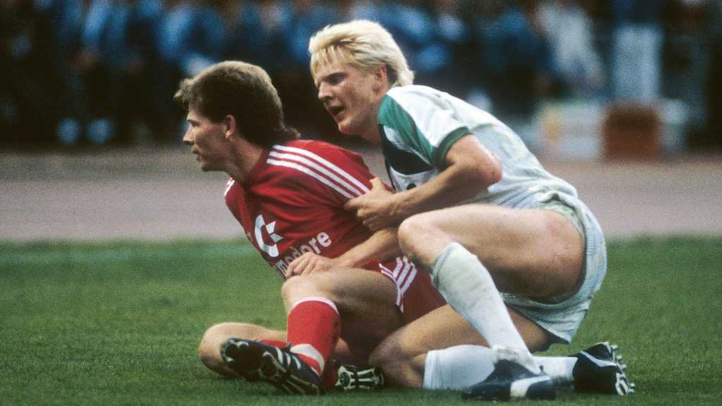 Stefan Reuter und Stefan Effenberg sitzen nach einem Zweikampf bei einem Spiel auf dem Rasen