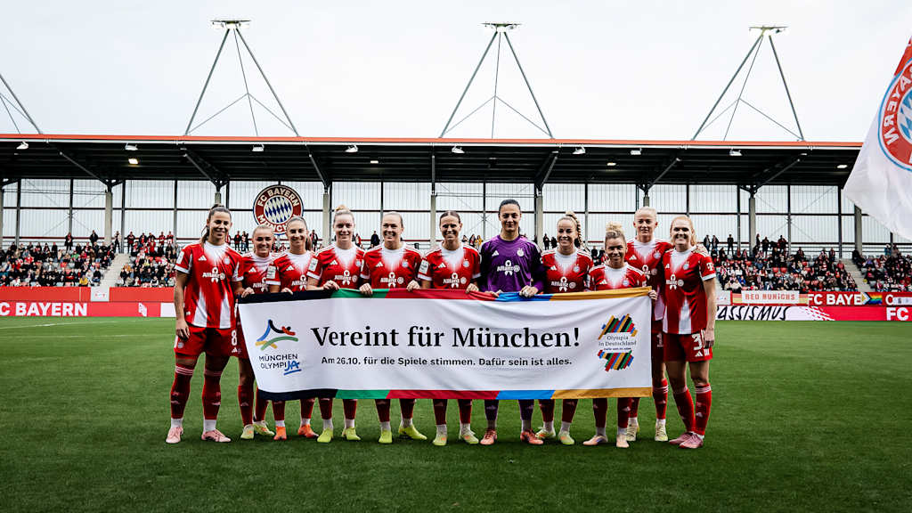 Die Spielerinnen der FC Bayern Frauen halten ein Banner mit der Aufschrift „Vereint für München – OlympiJa!“ vor dem Heimspiel der FC Bayern Frauen in der Google Pixel Frauen-Bundesliga gegen den 1. FC Köln