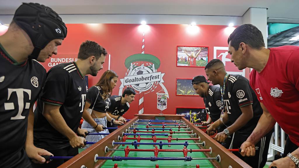 Lúcio spielt in Brasilien Tischkicker mit Personen in Bayern-Trikots