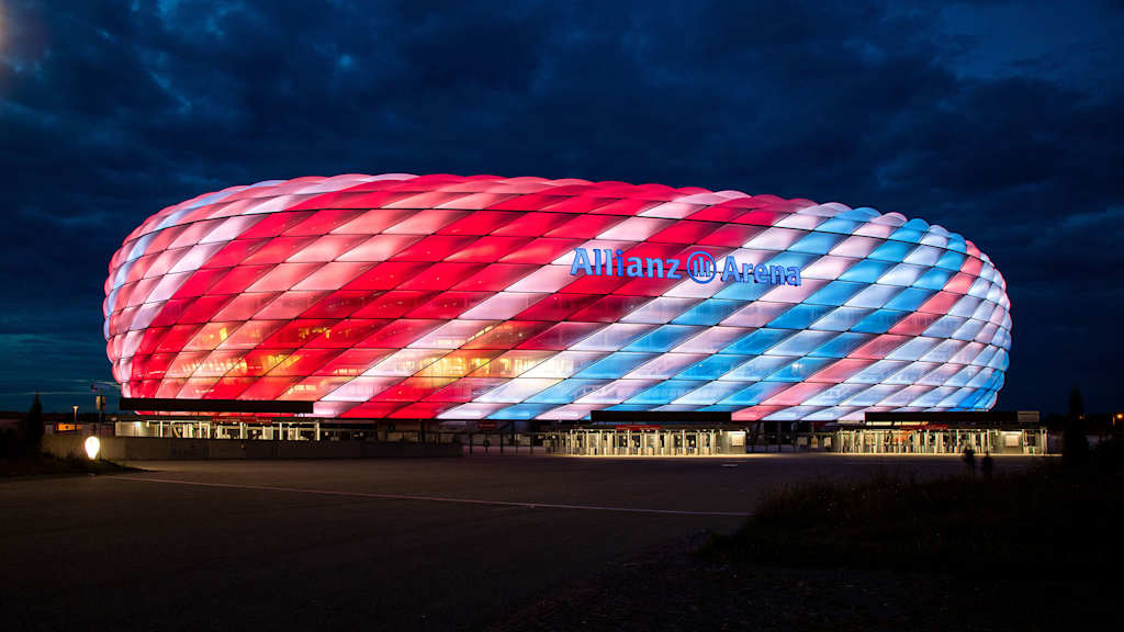 Die Allianz Arena leuchtet in der Nacht mit Klimastreifen auf der Fassade