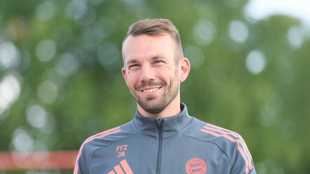 Jérôme Reisacher lächelnd auf dem Weg zum Training am FC Bayern Campus.