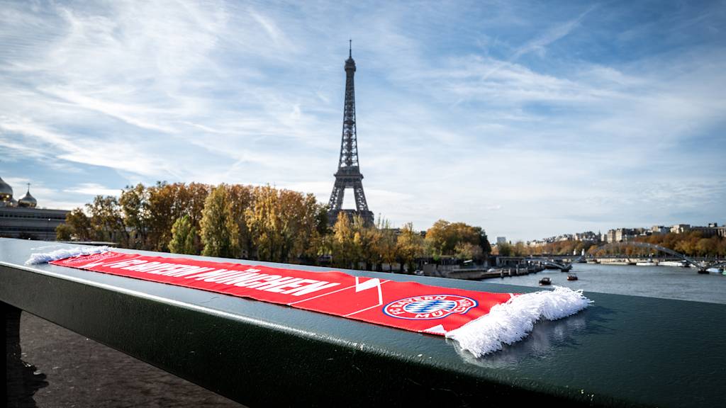 Ein FC Bayern-Schal liegt auf einer Brücke mit Blick auf den Eiffelturm.