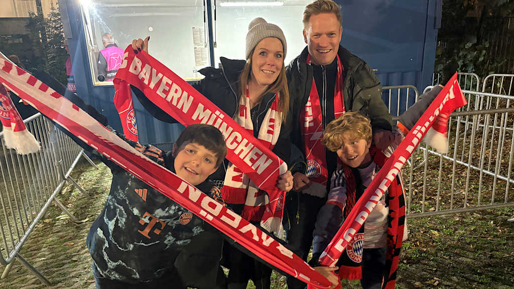 Eine Familie aus Fans des FC Bayern strecken ihre Schals in die Höhe