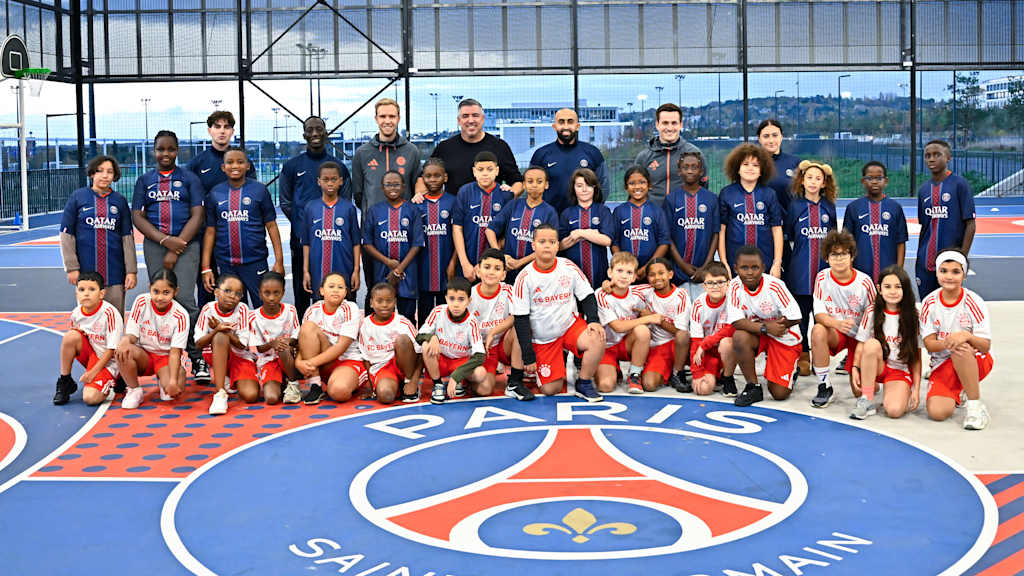 Jugendliche mit Trikots von PSG und FC Bayern gemeinsam mit den Coaches, darunter Roy Makaay, posieren für ein Foto