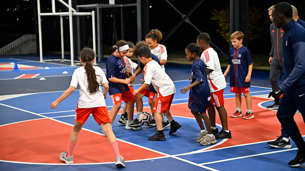 Kinder spielen in PSG- und FCB-Trikots gegeneinander Fußball