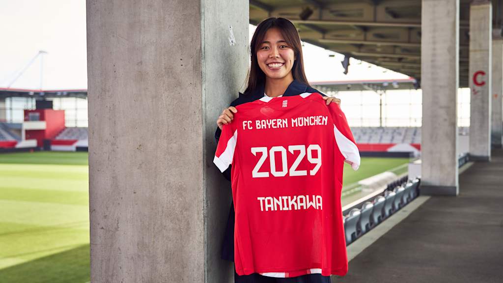 Momoko Tanikawa holds up her Bayern jersey with 2029 printed on the back.