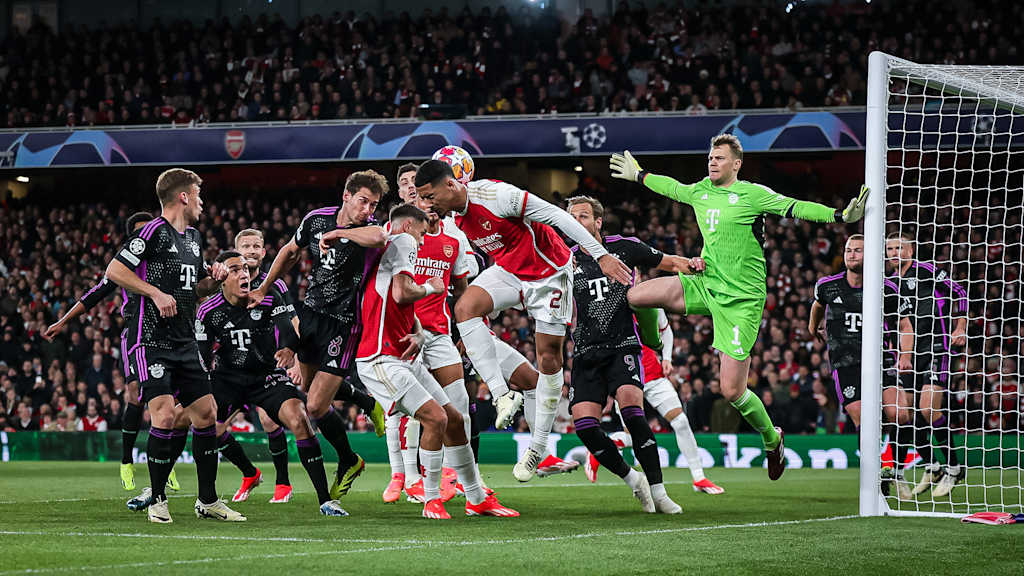 Verschiedene FC Bayern-Spieler in Schwarz und Arsenal-Spieler in Rot gehen zum Ball. Manuel Neuer steht in Grün im Tor.