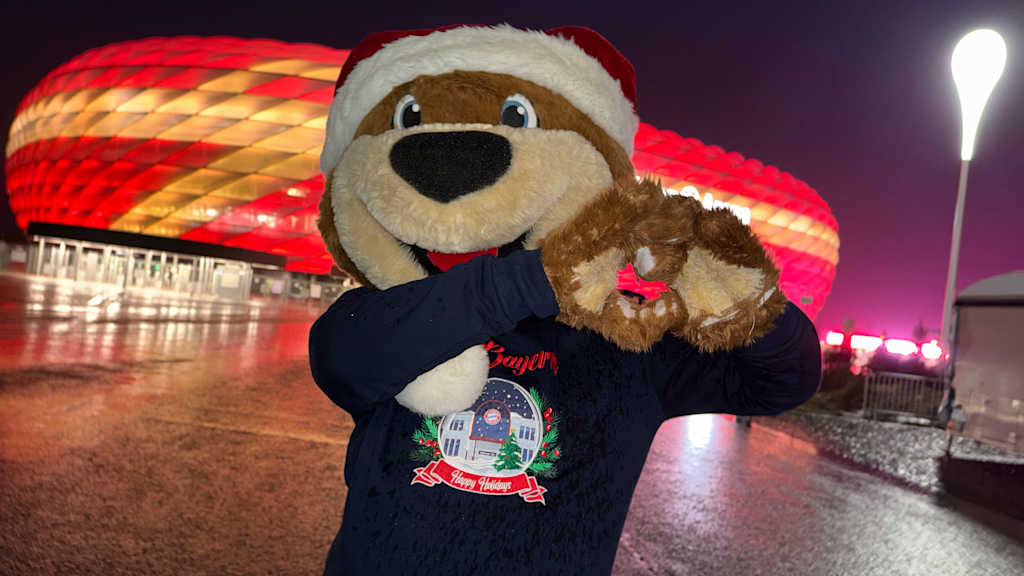 Berni vor der Allianz Arena, wie er ein Herz mit seinen Tatzen zeigt.