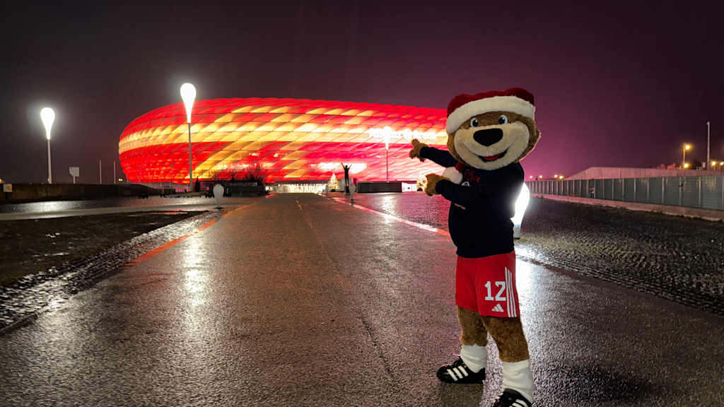 Berni zeigt auf die beleuchtete Allianz Arena.