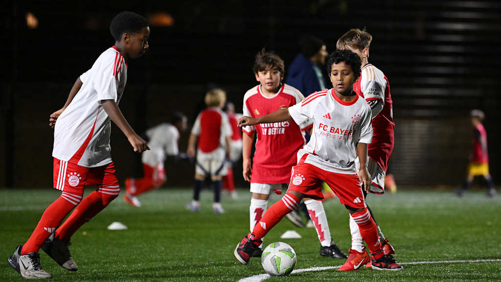 Kinder in FC Bayern- und Arsenal-Trikots spiele Fußball im Rahmen Gruppenfoto beim Kindertraining im Rahmen von Arsenal in the Community