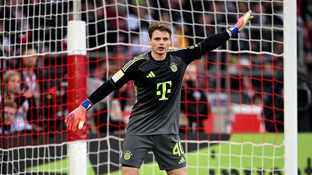 Jonas Urbig zeigt mit seinem Arm nach oben im Spiel gegen den VfB Stuttgart