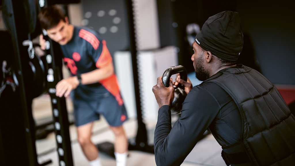 Alphonso Davies doing strength exercises with a weighted vest during his rehab