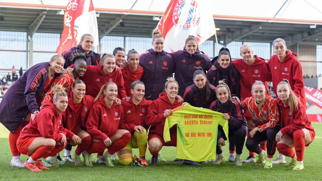 Die FC Bayern Frauen halten ein Trikot mit einer Botschaft für Mala Grohs in die Höhe.