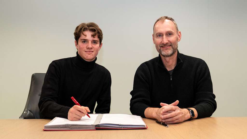 Xaver Pucci unterzeichnet seinen neuen Vertrag und blickt dabei in die Kamera.