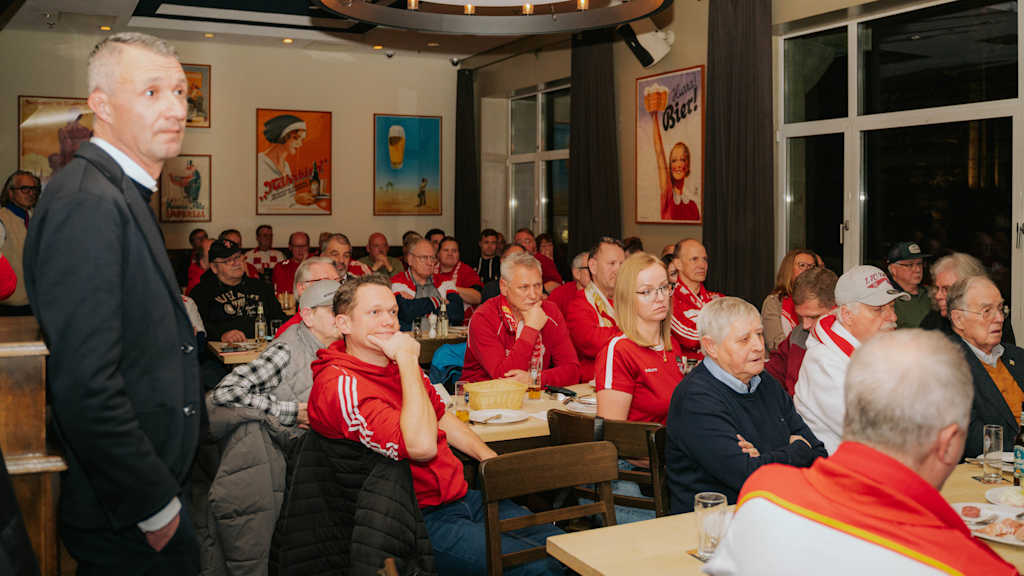 Zahlreiche Bayern-Fans sitzen in einem Saal.