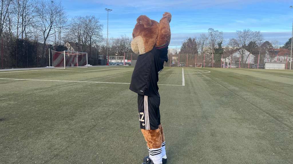 Berni auf dem Kunstrasenplatz und macht eine Yogaübung.