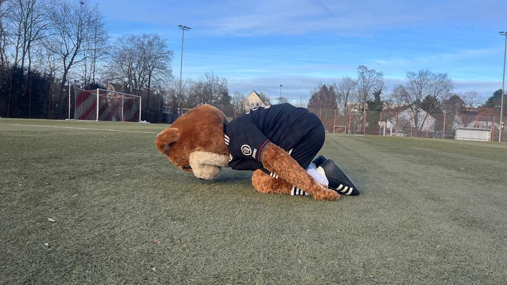 Berni auf dem Kunstrasenplatz und macht eine Yogaübung.