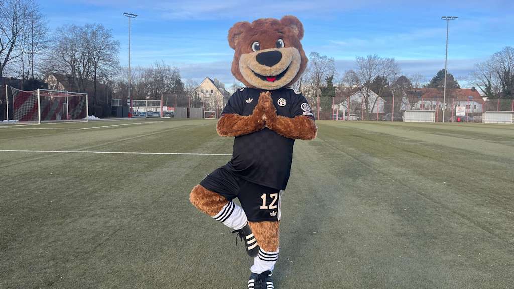 Berni auf dem Kunstrasenplatz und macht eine Yogaübung.