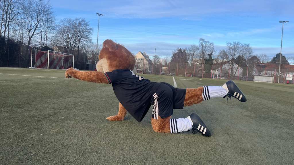 Berni auf dem Kunstrasenplatz und macht eine Yogaübung.
