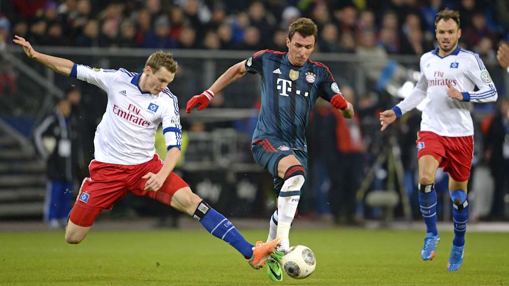 Marcell Jansen in Weiß grätscht gegen Bayerns Mario Mandzukic in Blau.