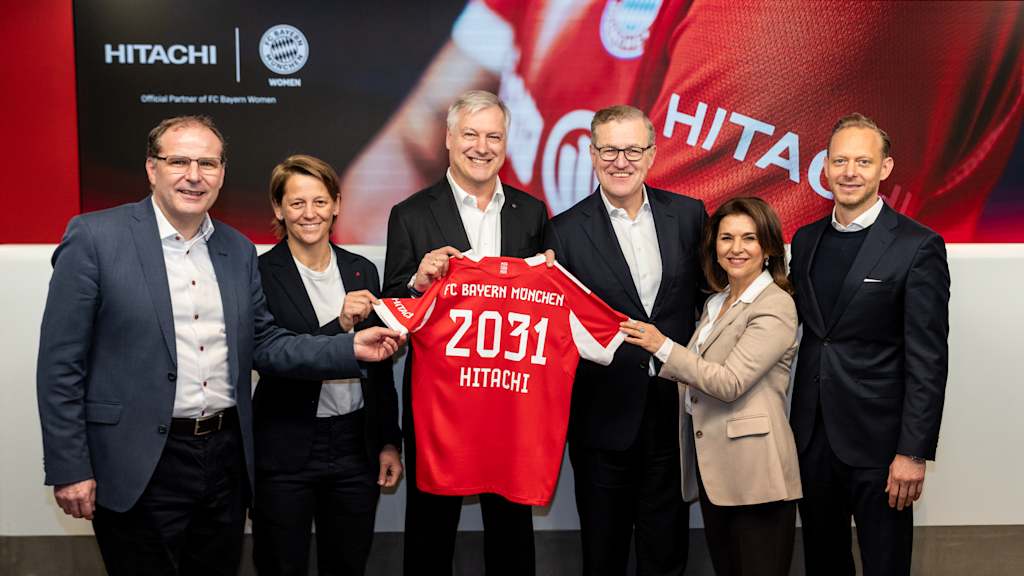 Die Verantwortlichen des FC Bayern und Hitachi Energy halten ein Trikot mit der Aufschrift 2031 in die Kamera.