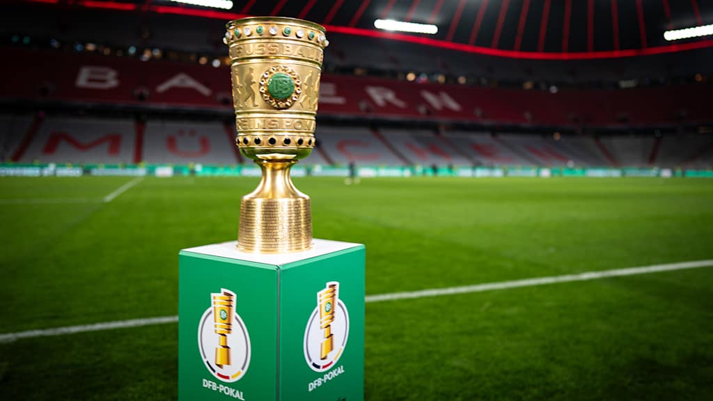 Trophäe des DFB-Pokals auf einem Podest vor dem Rasen in der Allianz Arena