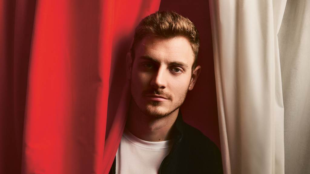 Josip Stanišić entre un telón rojo y blanco