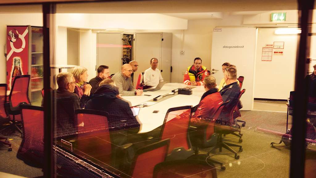 Rettungssanitäter besprechen sich an einem Konferenztisch während eines Spiels des FC Bayern in der Allianz Arena