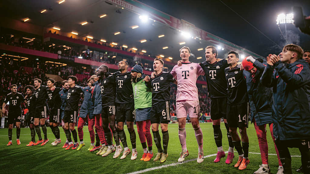 Bayern-Spieler jubeln Arm in Arm vor der Fankurve nach dem Sieg im DFB-Pokal bei Union Berlin