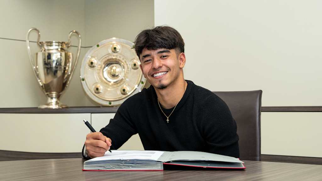 Maycon Cardozo hält bei der Vertragsunterschrift lächelnd einen Stift in der Hand.