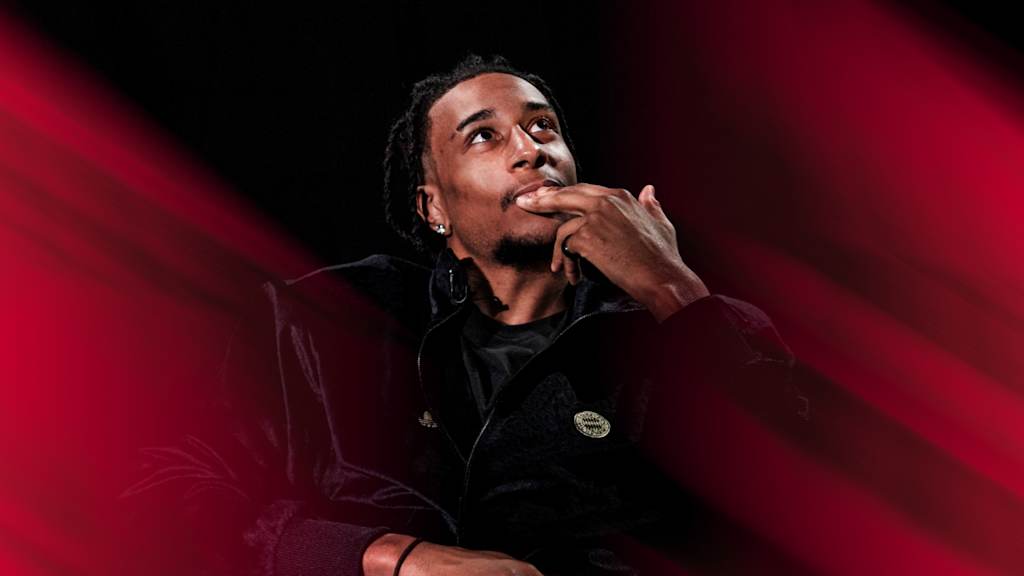 Michael Olise in einem schwarzen Oberteil blickt nach oben.