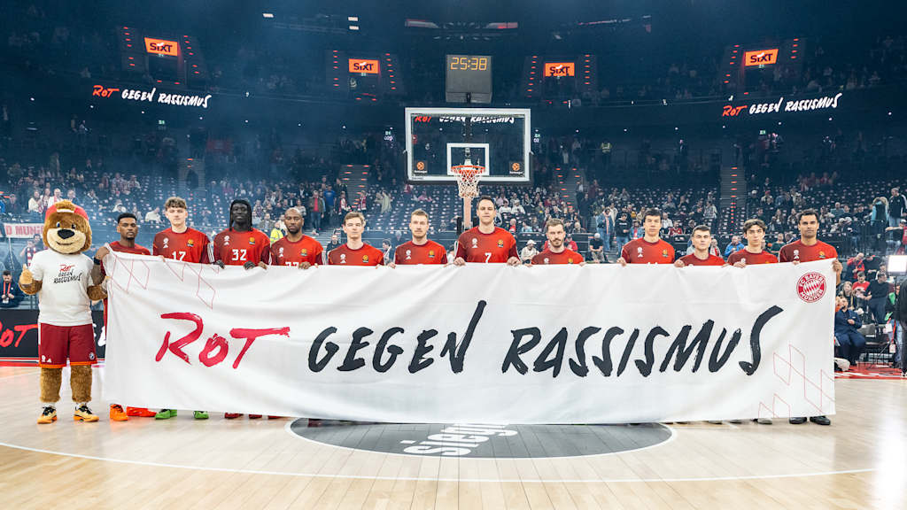 The Bayern players are holding a banner that reads “Red Against Racism”