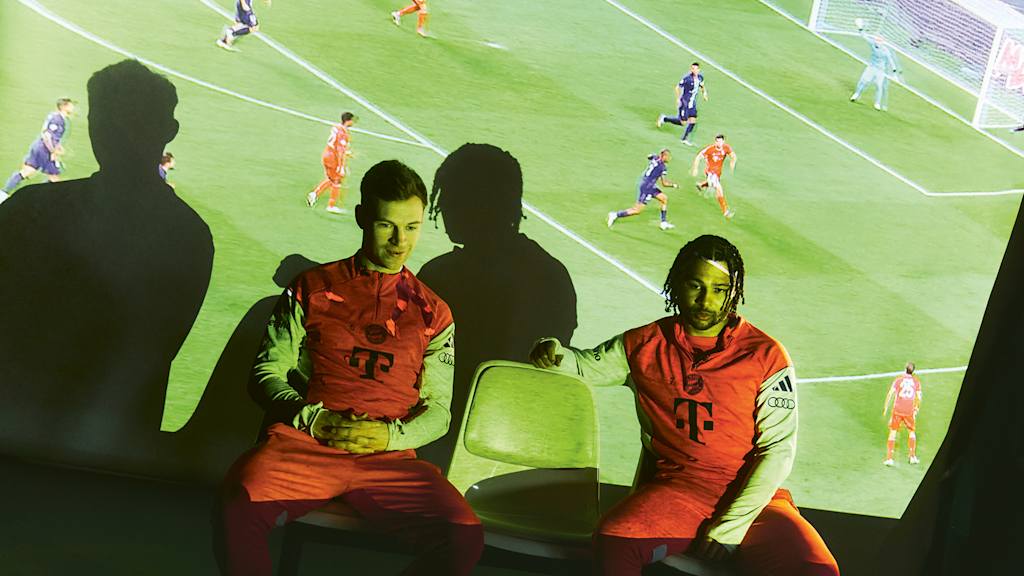 Joshua Kimmich und Serge Gnabry beim TV-Abend - auf einer Leinwand hinter ihnen sind Ausschnitte großer Bayern-Triumphe zu sehen
