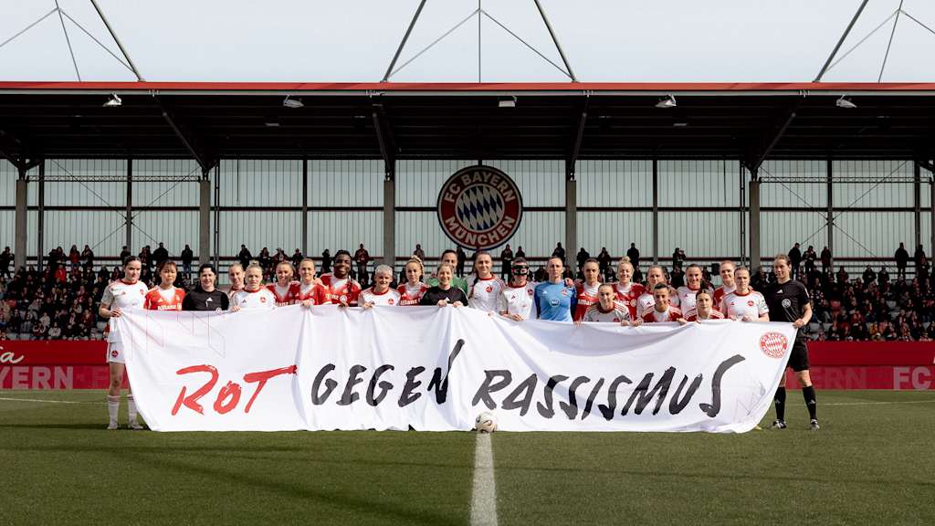 Spielerinnen vom FC Bayern und dem 1. FC Nürnberg halten ein Banner mit dem Schriftzug Rot gegen Rassismus