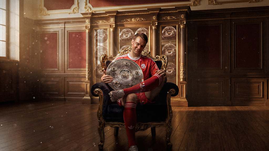 Manuel Neuer sitzt mit der Meisterschale in einem Sessel.