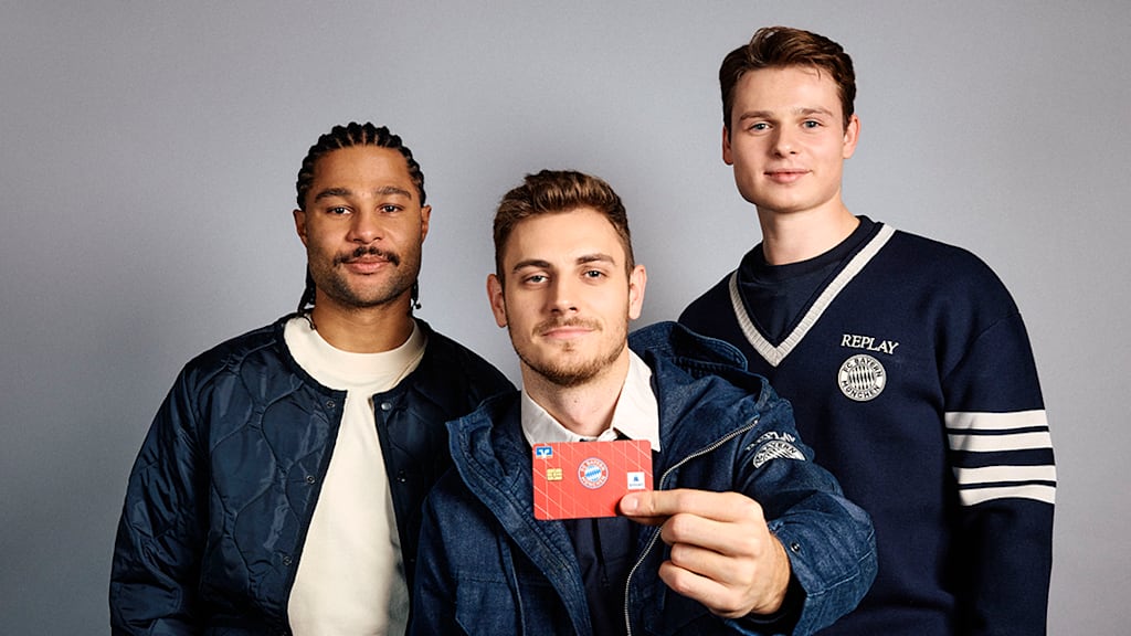 Gnabry, Stanisic, Urbig halten eine Bankkarte in der Hand