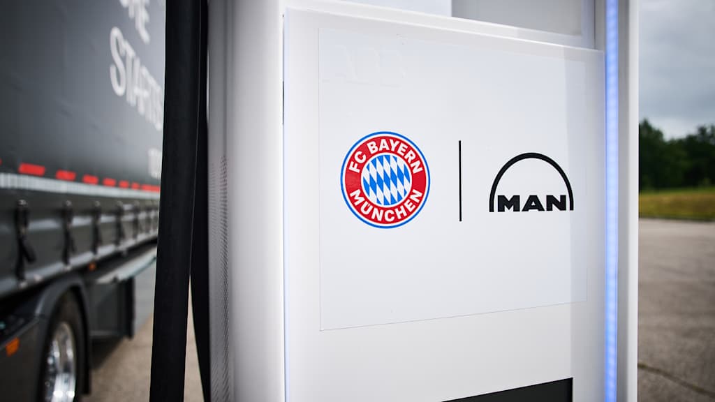Logos des FC Bayern und MAN auf einer Ladesäule an der Allianz Arena