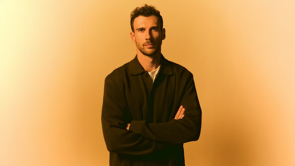 Leon Goretzka verschränkt die Arme vor einer gelben Leinwand