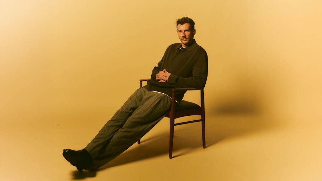 Leon Goretzka sitzt locker auf einem Stuhl, die Beine ausgestreckt