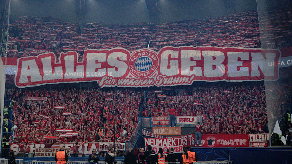 Bayernfans im Fanblock mit dem Schriftzug "Alles geben - für unseren Traum"