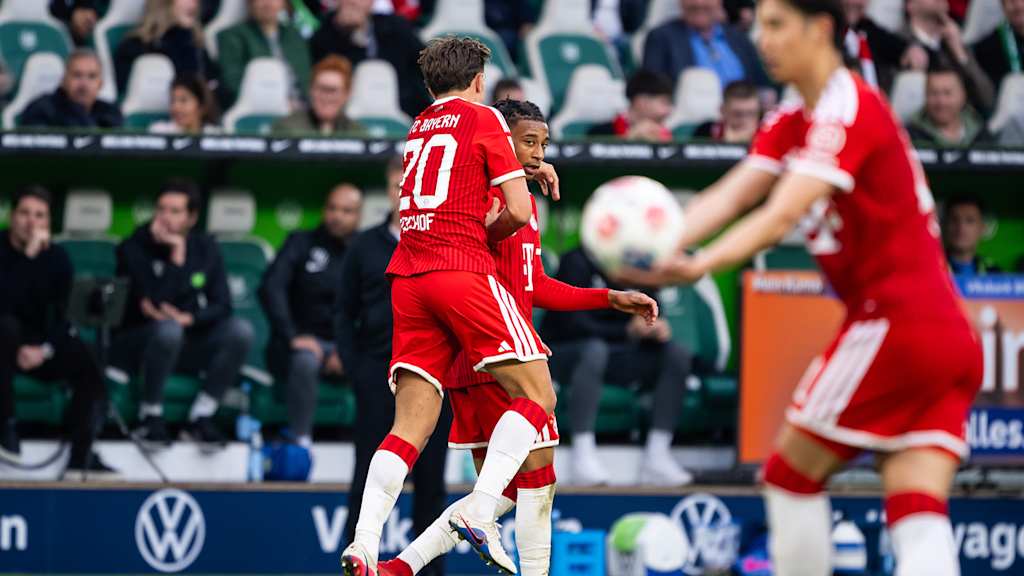 Tom Bischof springt auf Michael Olise nach dem 1:= im Bundesliga-Spiel des FC Bayern beim VfL Wolfsburg