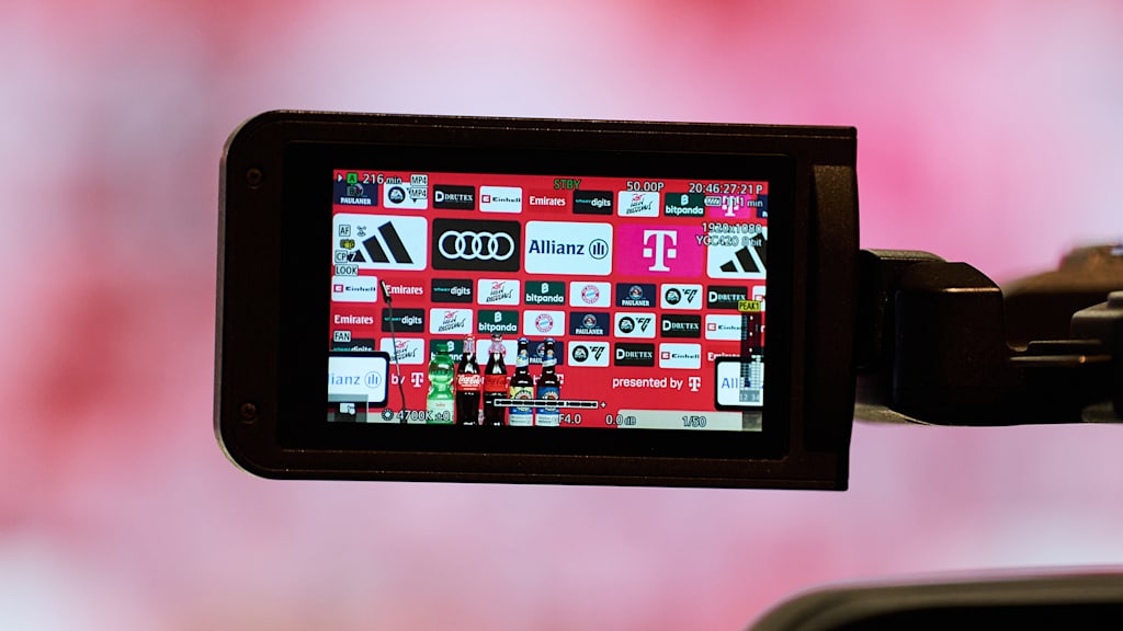 Auf dem Display einer Kamera ist die Sponsorenwand im Medienraum des FC Bayern zu sehen