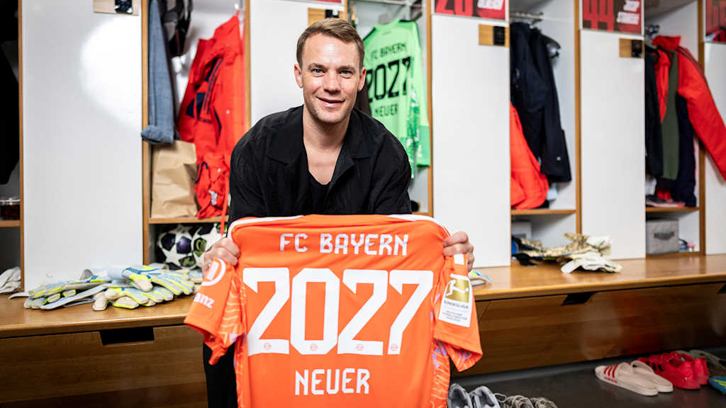 Manuel Neuer hält ein orangenes Torwarttrikot mit 2027 Neuer