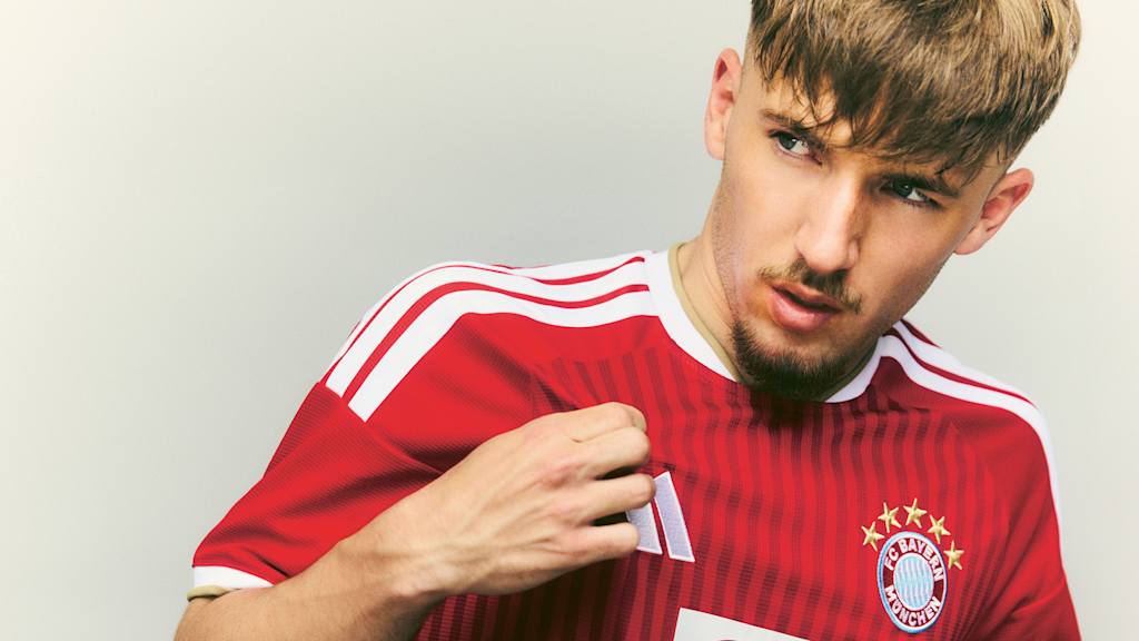 Lennart Karl trägt ein FC Bayern Trikot in rot