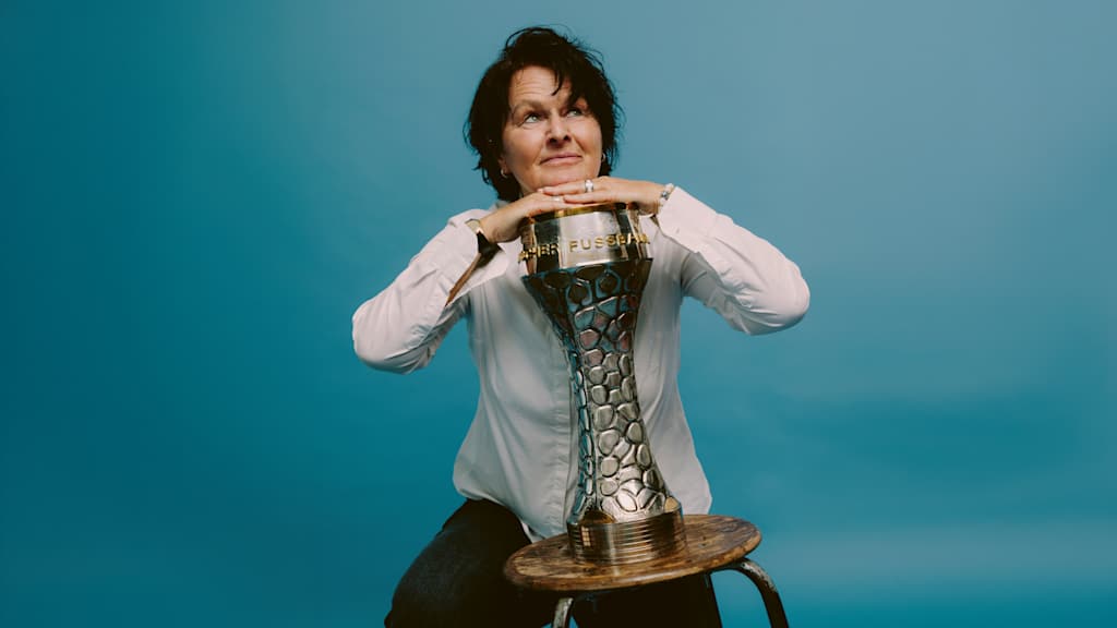 Sissy Raith mit dem 76erPokal vor blauem Hintergrund.