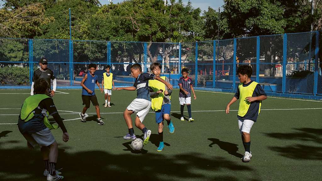 Jugendliche spielen Fußball auf einem Kunstrasenplatz in Kolumbien