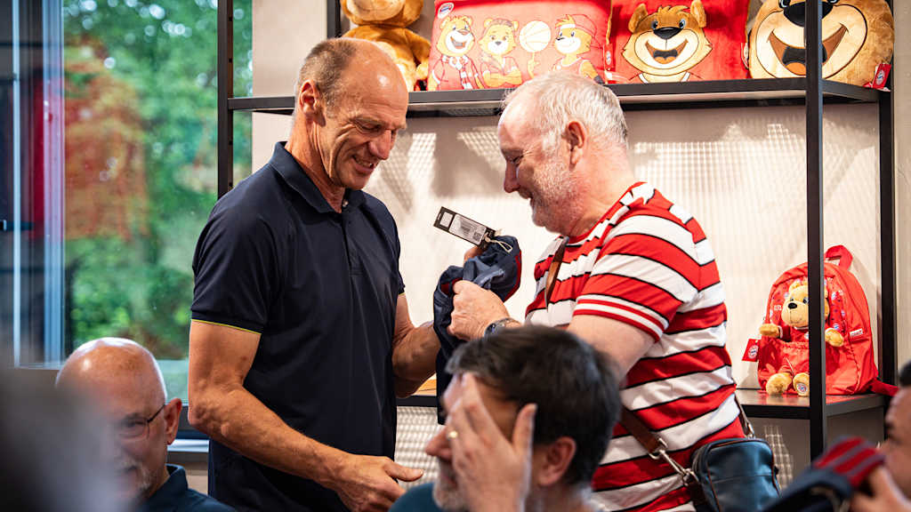 Hans Pflügler übergibt ein Shirt an einen Fan des FC Bayern