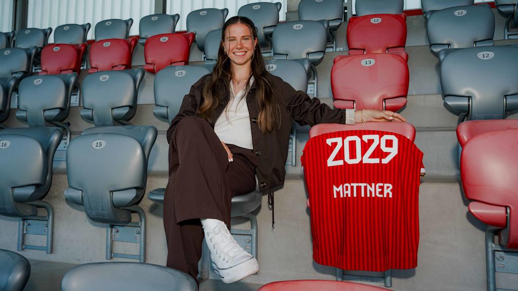 Sarah Mattner sitzt auf der Tribüne am FC Bayern Campus und lächelt in die Kamera.