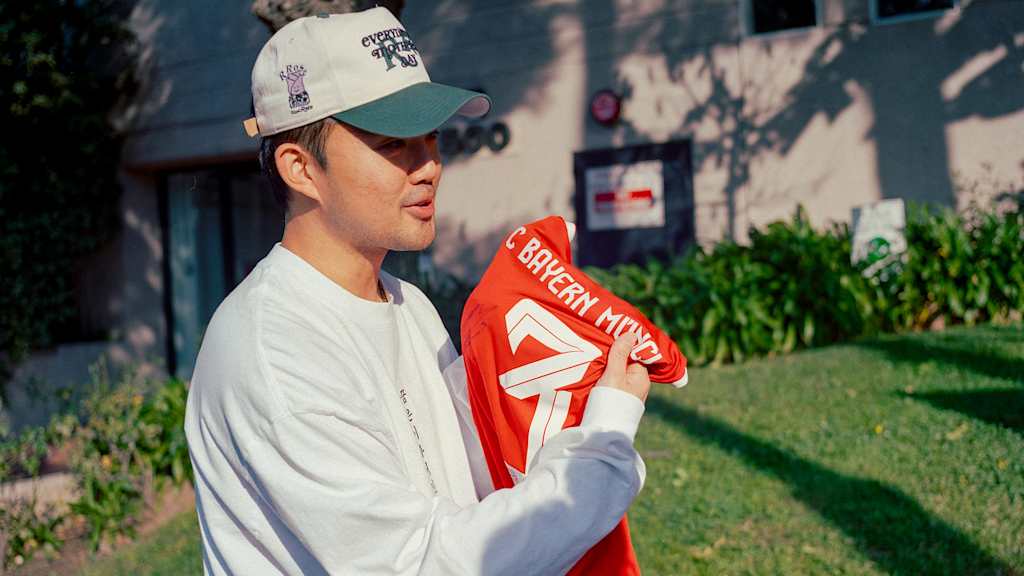 Ein Mann mit einer Cap hält ein FC Bayern Trikot